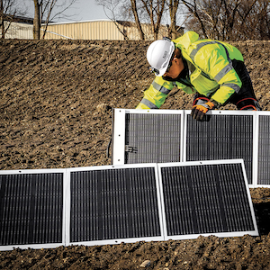 Worker setting up Klein Tools' portable solar panels on jobsite